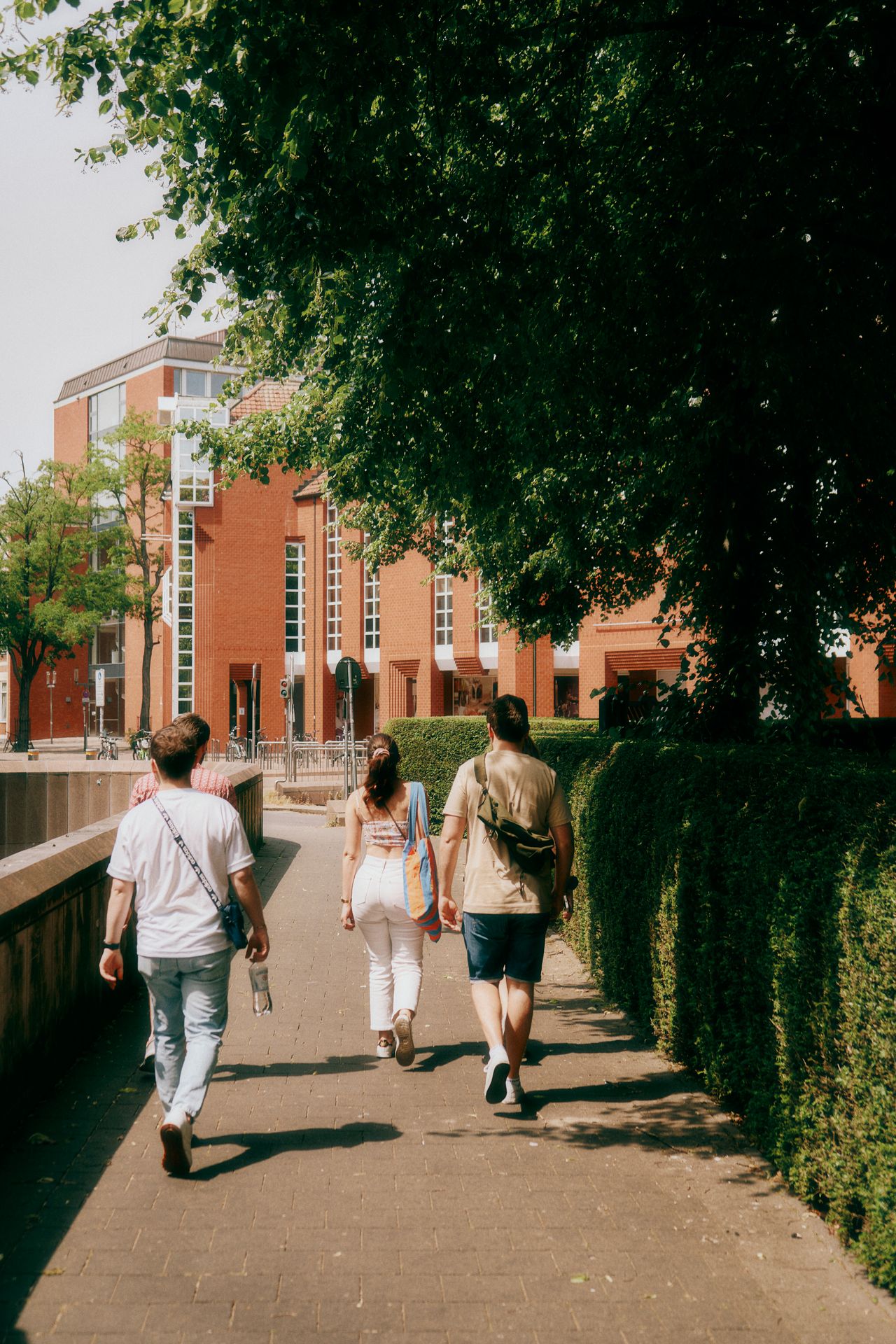 Group of students walking on the walkway in front of a university building